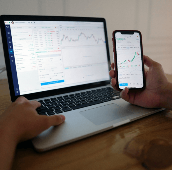 a caucasian hand viewing charts on mobile and on pc